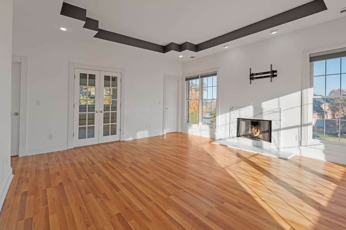 The second level primary bedroom suite is filled with natural sunlight also. An accented tray ceiling continues the decorative theme of the home. Glass double doors access the ensuite bathroom and the two outside doors are walk-in closets.