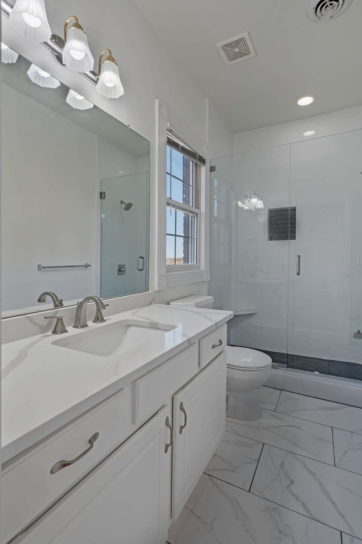 The bathroom in the second bedroom has the same finishes as the primary bathroom. It's a large shower as well.