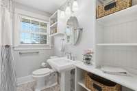Full bathroom with custom built in shelving for storage, pedestal sink, and shower