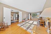 Sunlit flexible room with a wide picture window and hardwood floors, offering space for play, hobbies, or work. Neutral tones keep the room versatile for a variety of uses.