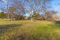 Expansive yard featuring established trees and generous open areas suitable for play, gardening, or relaxation. The landscape provides a peaceful outdoor backdrop.