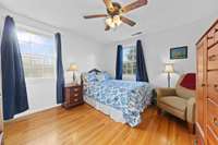 Comfortable bedroom with two windows, hardwood flooring, and space for a sitting area. Neutral finishes make furnishing easy.