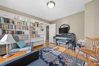 Inviting room with built-in shelving, hardwood floors, and ample natural light. The layout offers a comfortable space for reading, study, or music.