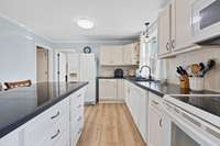 Bright kitchen with white cabinetry, tile-top island seating, and generous counter space. Multiple windows create a light, welcoming workspace.