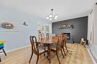 Dining room with updated flooring and a painted brick accent wall with mantel. The space opens to the kitchen for convenient flow.