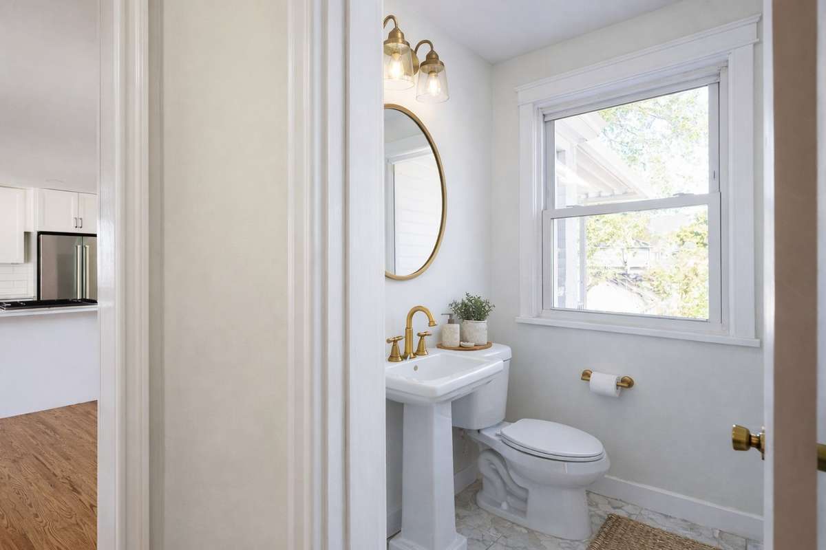 Parlor bath, located just outside of both living spaces. Brushed gold fixtures and marble tile floors. 
**Ai generated/Virtually staged photo**