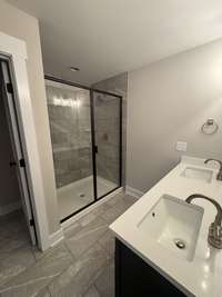 Primary bedroom has double vanities with quartz countertops  in primary bath as well as tiled shower.