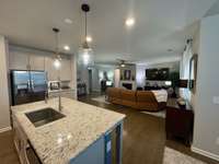 Open-concept view from the dining area showcases the granite island with farmhouse sink, brand-new garbage disposal, and seamless connection to the living room.
