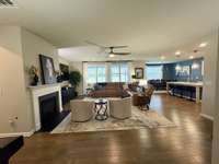 Spacious open-concept living area with hardwood floors, gas fireplace, and natural light,  perfect for entertaining or relaxing with family and friends.