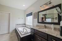 The bathroom off the primary bedroom boasts  his and hers vanities and a jacuzzi tub to relax in at the end of a long day ! The door you see in this photo is a large walk in closet.