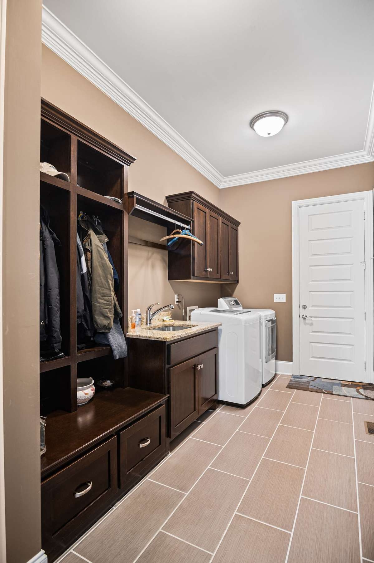 Designed for ultimate efficiency, the generous 7'x15' utility room boasts a wealth of built-in storage. Ample cabinetry and closets, paired with a functional cubby for shoes & outerwear, create a beautifully organized space where cleanliness is done.