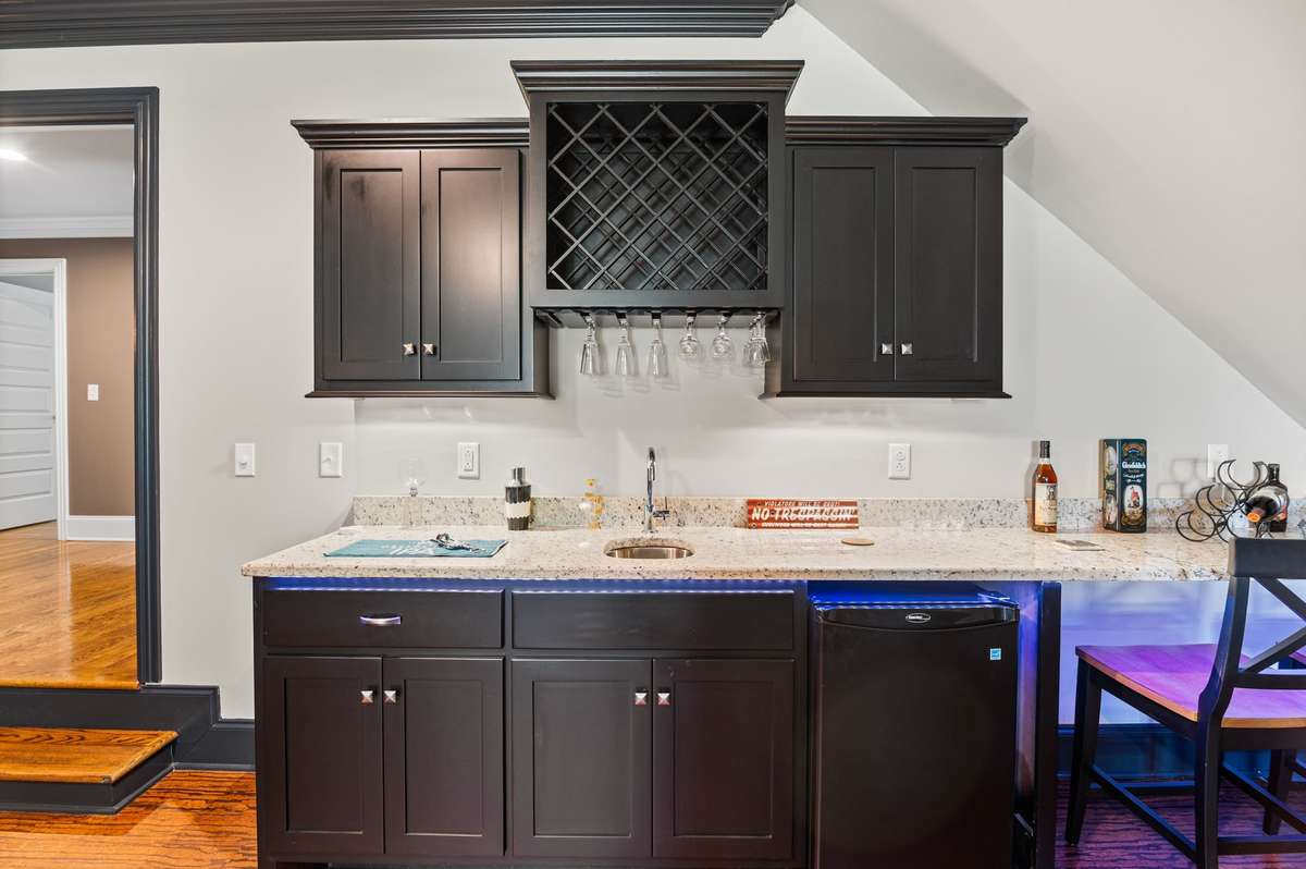 In this boundless media room, where cinematic adventures meet epic game nights, the extended wet bar, mini-fridge, and abundant cabinets conjure every desired refreshment and treat. The magic of the evening need never pause.