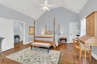 This view of the Primary Bedroom shows the vaulted ceiling, new ceiling fan and gleaming hardwood floors. The door opens to an "extra" closet.