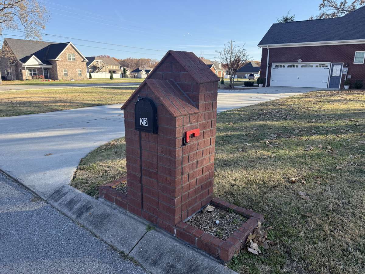 A custom brick mailbox is located at the end of the driveway.