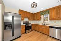 Main Floor- Kitchen- wood flooring, oak cabinetry, dishwasher, gas stove, oven, side by side refrigerator, recessed lighting