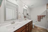 Primary bath has double vanities, tile floors and tub/shower combination.