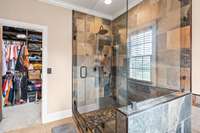 Custom tile walk in shower with custom built closet shelving in the huge primary walk in closet