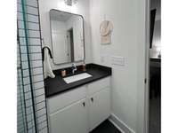 Full bath with walk-in framelss shower and black quartz countertop