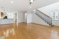 Great room looking from far front corner. Dining room area to far left with kitchen beyond. Soaring foyer with stairs to second level.