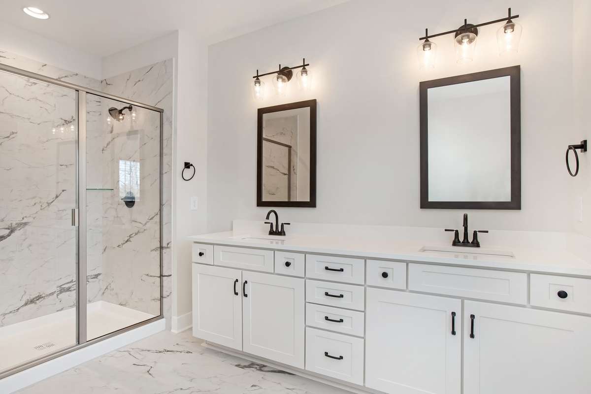 Picture is of the Madison Americana built on another lot. Gorgeous primary bathroom with double vanities, tiled shower and quartz countertops. Soft close drawers and cupboards even in the bathroom!