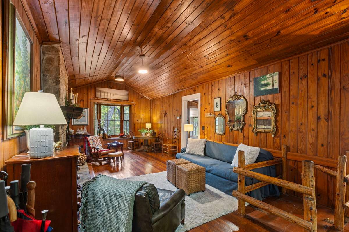 The doors open to pine-lined walls and ceilings that create a warm, cozy atmosphere, while the spacious great room allows for multiple seating arrangements, ideal for a gathering or relaxing by the fire.