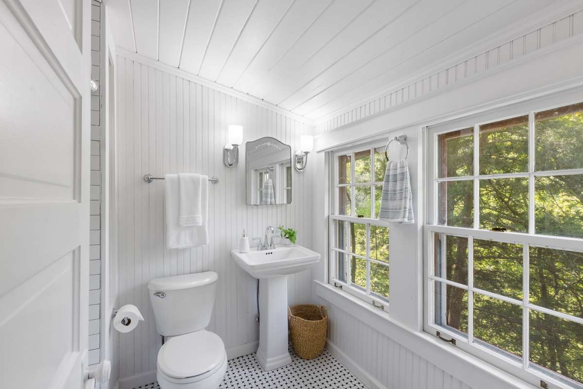 The bathroom has been recently undergone a full renovation with new tile flooring, a pedestal sink, vanity lights, towel bars, and a subway tile surround in the tub/shower combination—all complemented by new plumbing fixtures and pex supply lines.