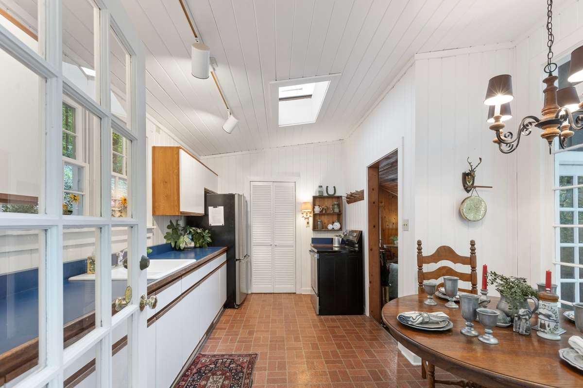 The fully functional kitchen features Formica countertops, a new GE electric stainless steel range w/ a ceramic cooktop.  There is refrige and freezer. Two windows above the sink frame peaceful views of the lush rear of the property.