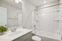 Secondary en-suite bathroom featuring a tub/shower combo and neutral, easy-to-maintain finishes.
