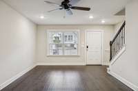 Another angle of the living room showcasing the open layout, easy flow to the kitchen, and the light-filled window overlooking the front patio and community sidewalks.