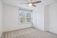 Secondary bedroom angle showcasing the closet and comfortable layout, complemented by natural light from the front-facing window.