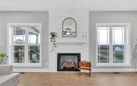 The shiplap gas fireplace serves as a stunning focal point, framed by two double windows that brighten the entire space.