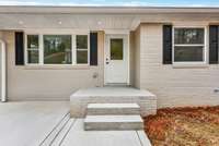Front porch stoop with new concrete patio beside it.