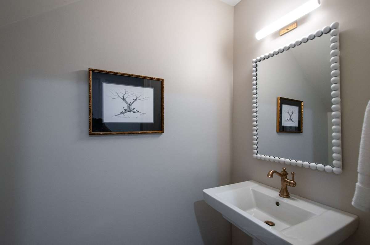 A powder room was created under the stairs and is outfitted with a stylish mirror and timeless fixtures.