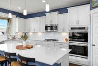 Expansive quartz island and abundant counter space,  gas cooktop, double ovens, and pantry are a few of the many features of this cook's kitchen.