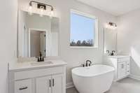 Relax and recharge in the freestanding soaking tub. Surrounded by tilework and positioned beneath a large window for natural light, this tub offers the perfect retreat for unwinding after a long day.