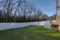 Step into your private retreat with this stunning fenced backyard, featuring a picturesque tree-lined view.