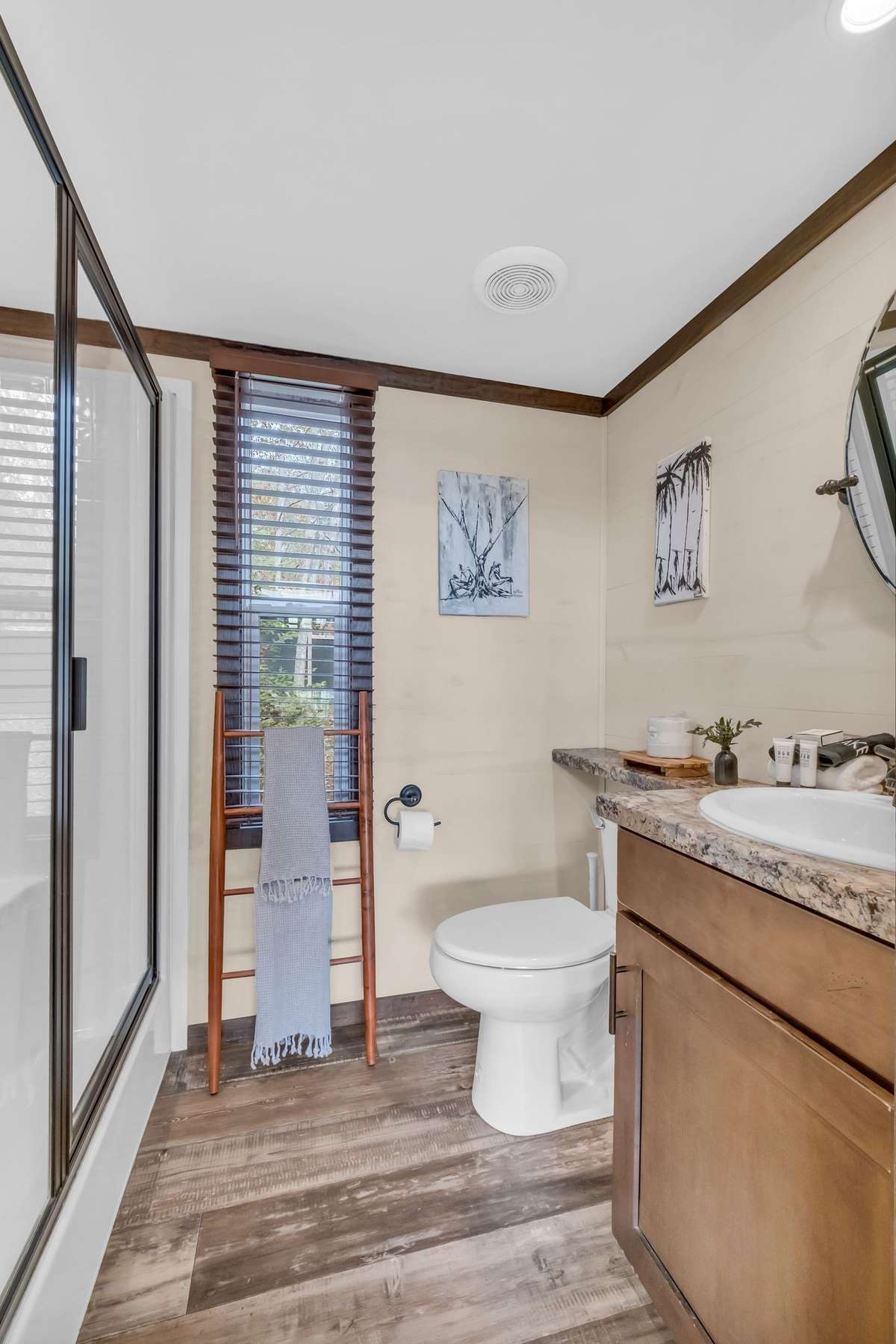 The full bathroom across the hallway from the built-in bunks offers ample counter space, a window, a vanity with storage and a walk-in shower