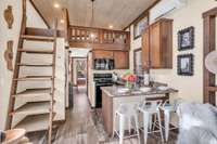 The living room opens up to the kitchen and the ladder on the left leads to the loft and offers additional space for storage or display