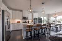 White and bright kitchen with open concept for entertaining. White timeless backsplash and beautiful Pottery Barn Pendants above kitchen island.