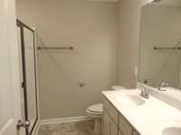 The primary bedroom comes with a modern shower, two sinks, and an elongated toilet, as well as a linen closet