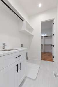 The laundry room includes a sink, hanging bar for drying, and custom built shelving.