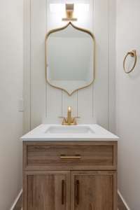Light powder room with shiplap accent wall and gold hardware off of the entryway.