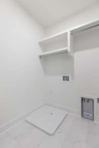 Laundry room includes a hanging bar and custom built-in shelving