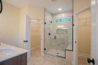 EXAMPLE>>>Primary Bathroom Features a Huge Tile Shower with a Bench and Window for Natural Lighting, Double Vanity and Two Walk-in Closets!
