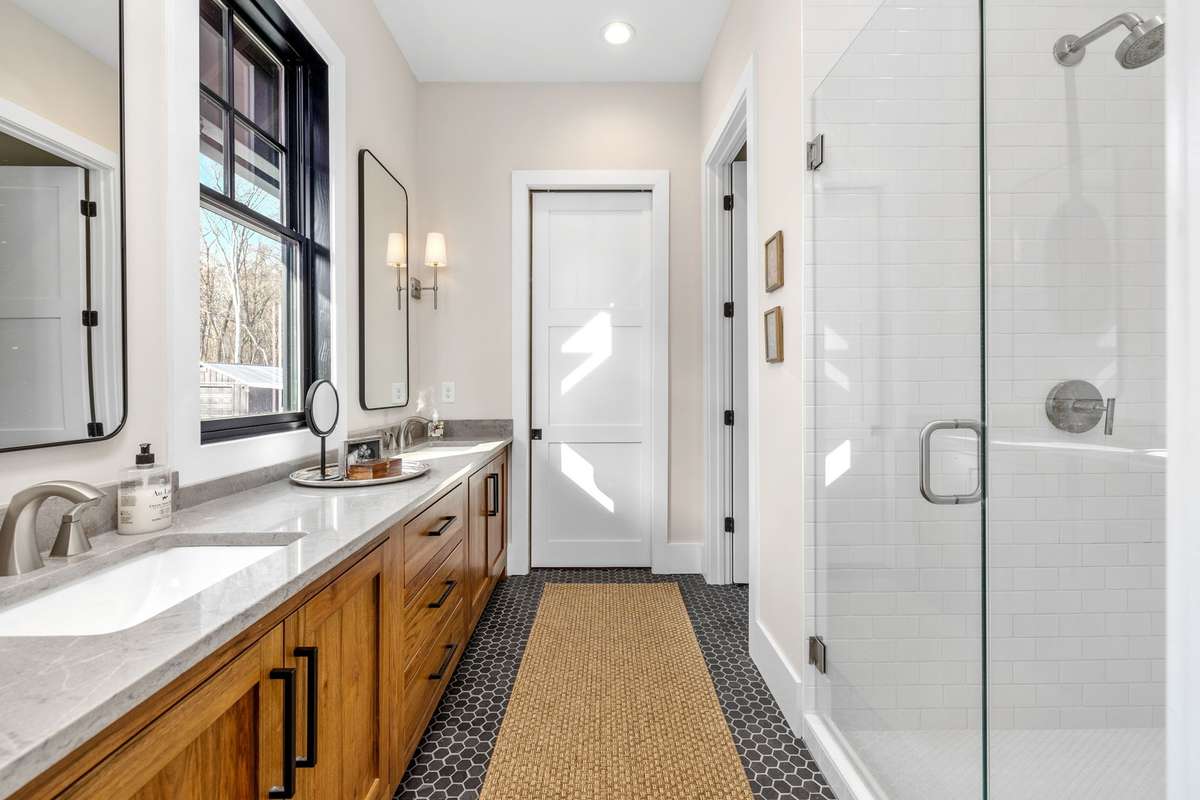 The master bathroom features milled Walnut from trees on the property. Huge cabinets, double sinks, and a separate area for everyone ensures a happy and stress-free life.
