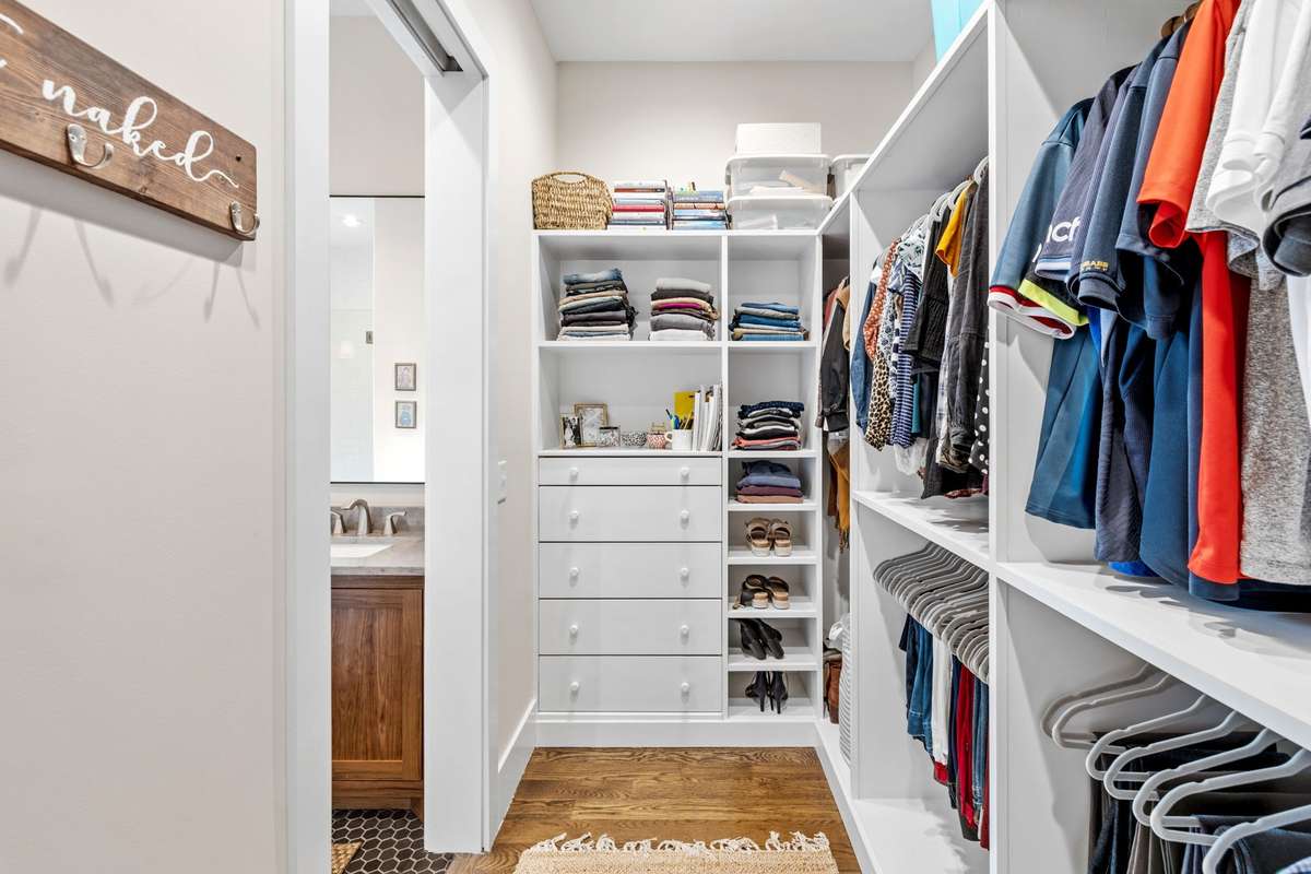 The primary closet is well designed with solid wood shelving and cabinetry galore. Every closet in this home has upgraded, solid wood shelving and cabinets.