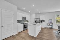 The gorgeous kitchen features a stunning island, sleek quartz countertops, a stylish backsplash, and stainless steel appliances.