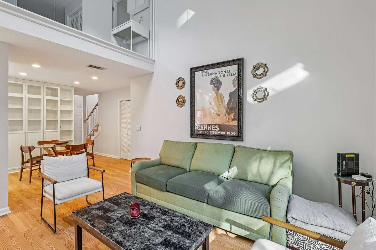The living area flows seamlessly into the dining and kitchen spaces. Beautiful hardwood floors, built-in shelving, and an airy loft above add to the open, modern feel.