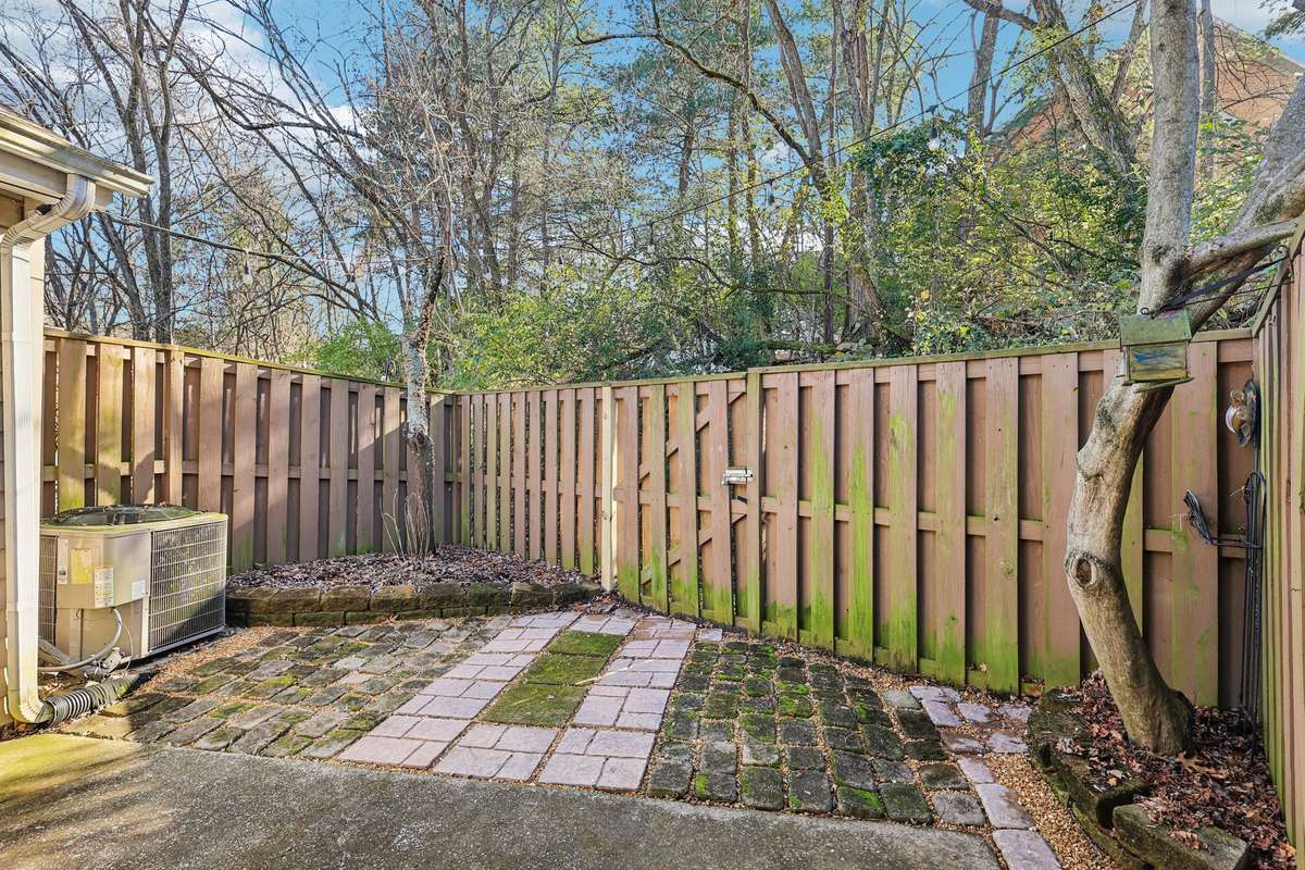 Fully fenced back patio with a mix of pavers and stonework, surrounded by mature trees for privacy. A peaceful outdoor retreat with room to garden, relax, or entertain.