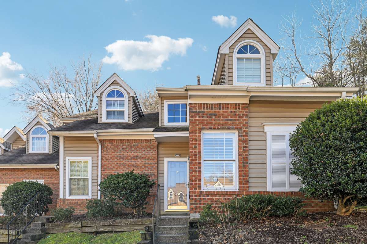 Inviting townhouse entry with brick façade and architectural details. Fresh landscaping and well-maintained shrubs enhance the welcoming feel.